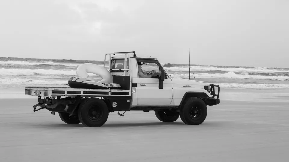 Black and white photograph of a four wheel drive on Fraser Island beach