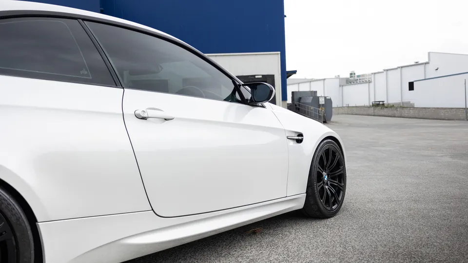 Close detail of a white BMW M3 wheel and body line