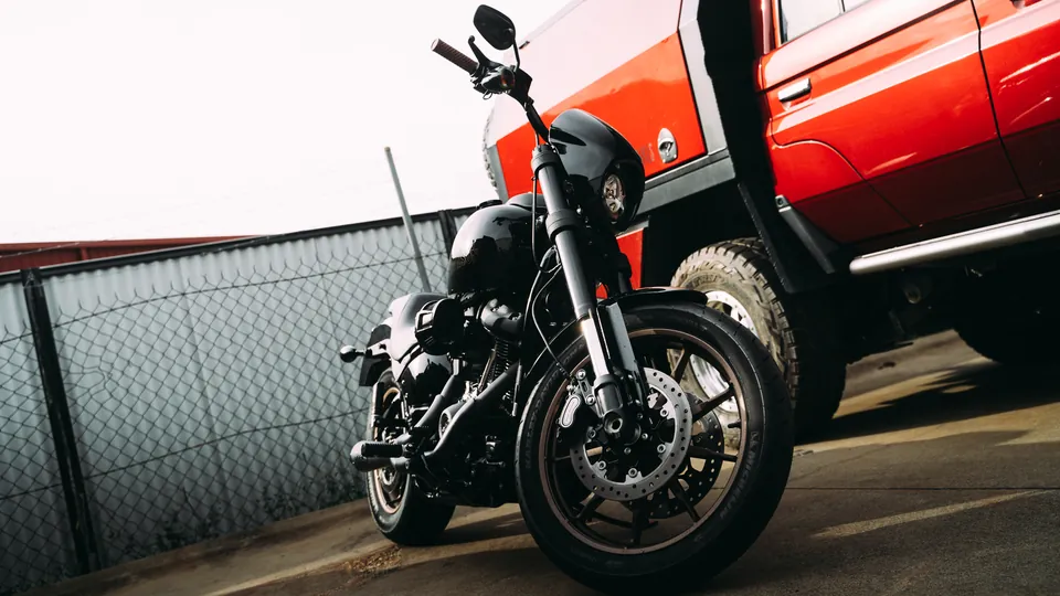 Motorcycle parked beside a red utility vehicle