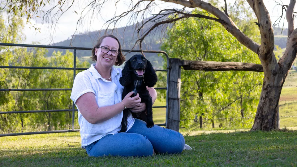 Woman holding a puppy beside a fence line