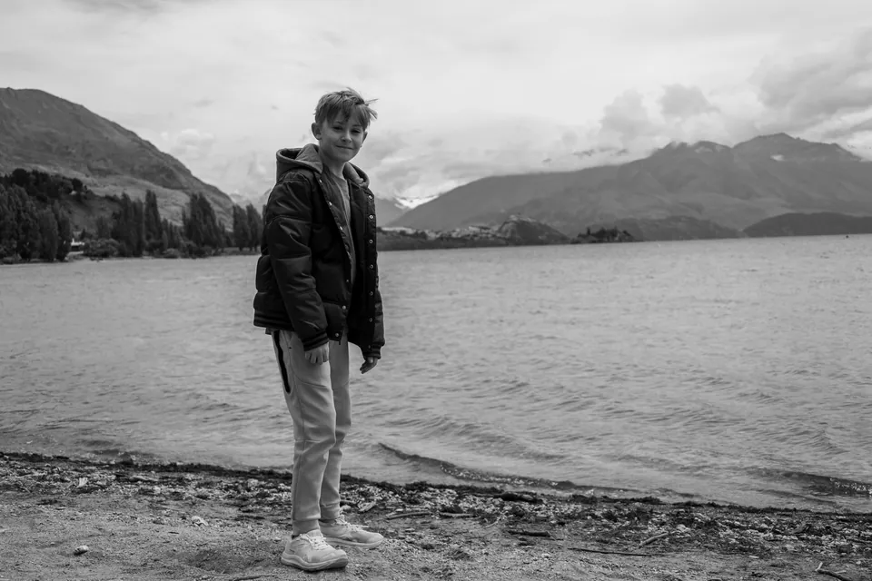 Black and white photograph of a person beside a still lake